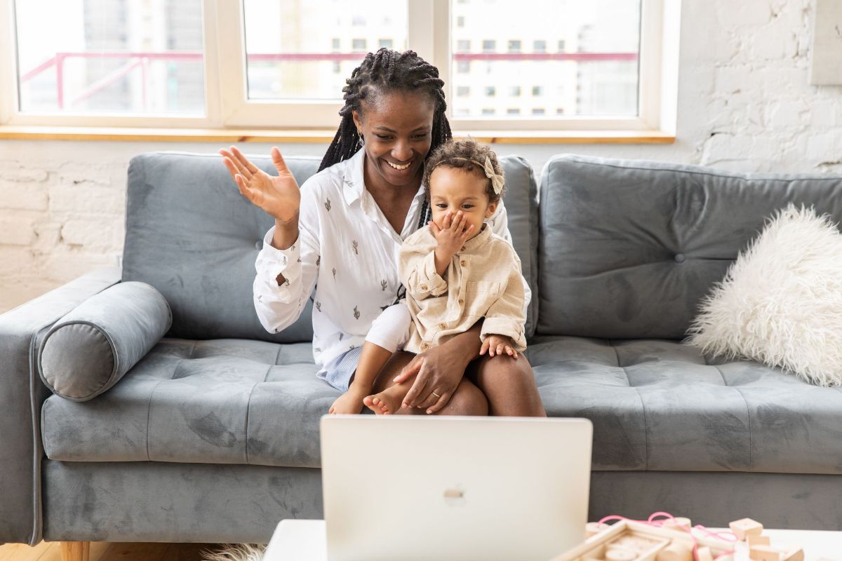 A mom and toddler waving on a video call